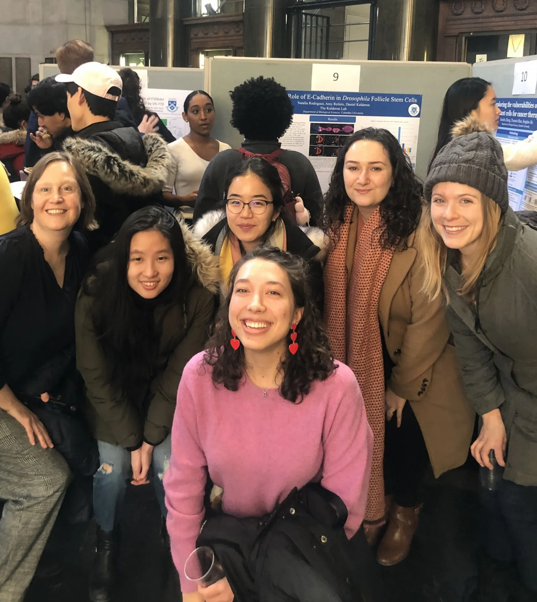 Lab members posing together in front of research posters at Nat's SURF poster presentation.