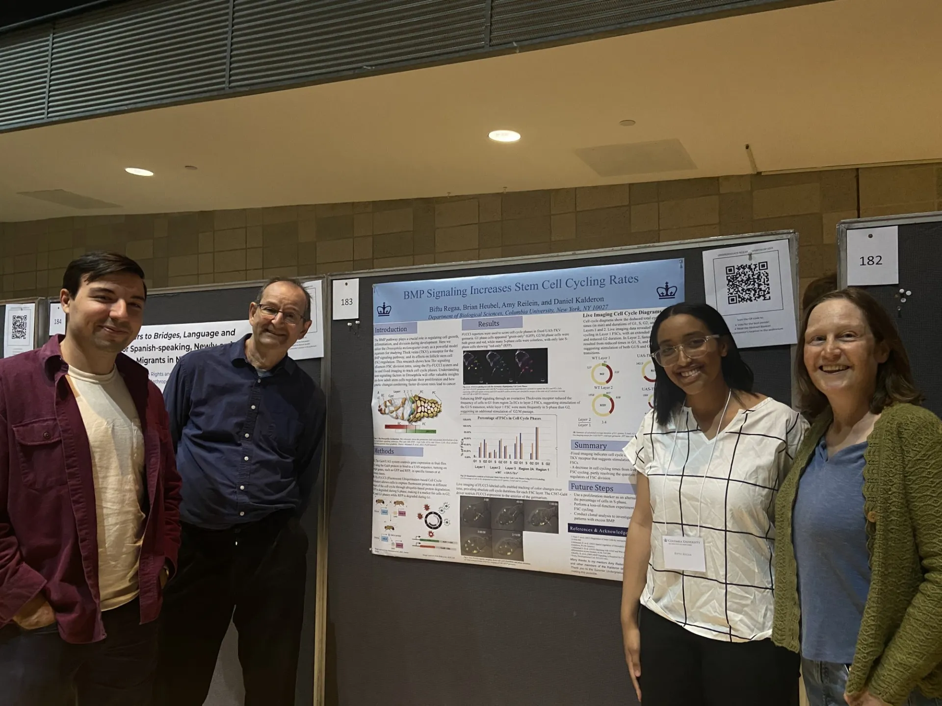 Four lab members standing beside a poster about BMP signaling and stem cell cycling at the undergraduate research symposium.